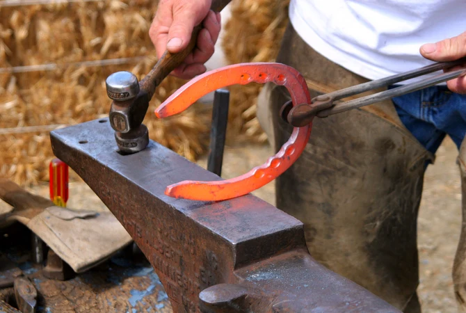A farrier shaping a horseshoe on an anvil